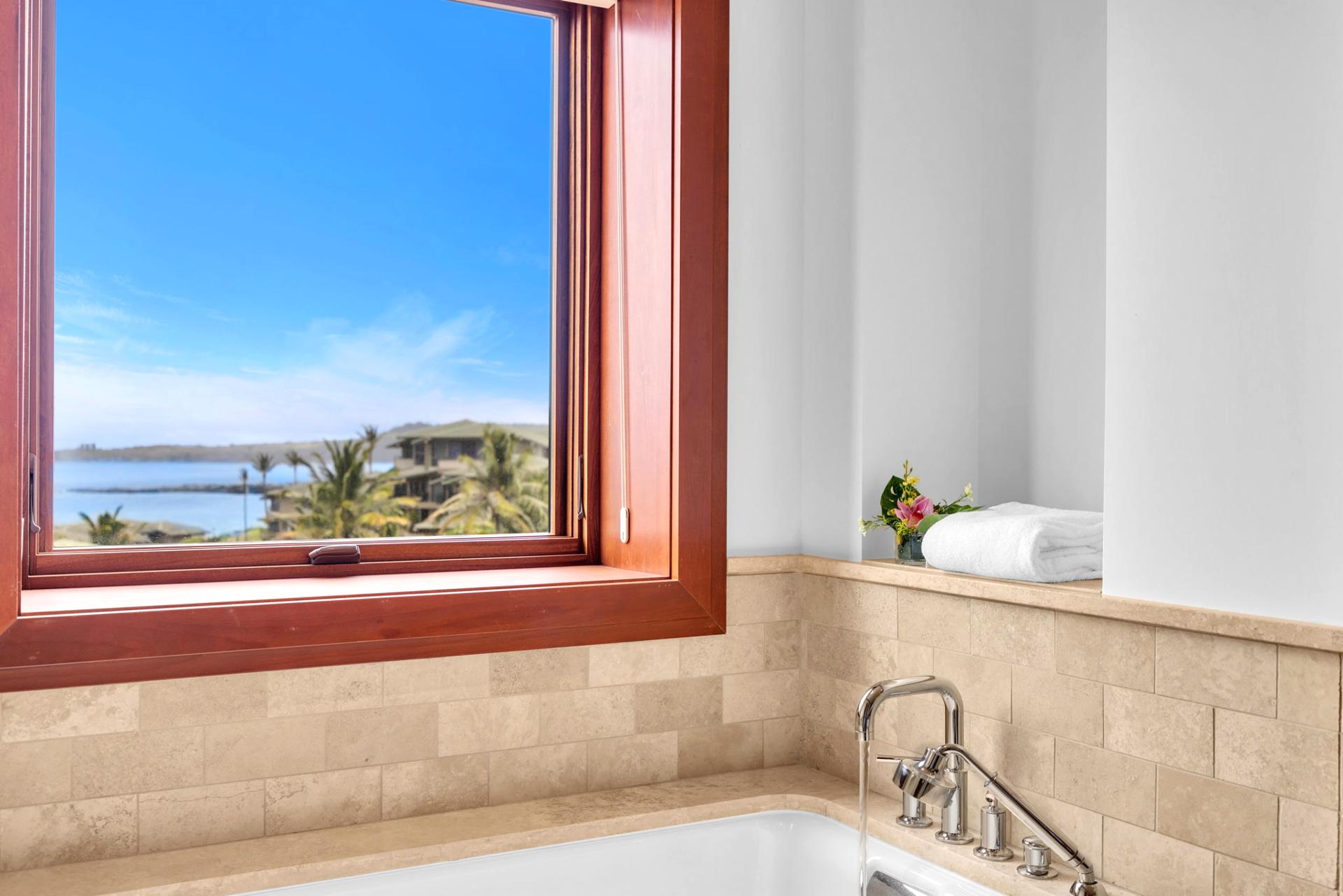 Cozy tub tucked under a scenic window with natural stone tiling
