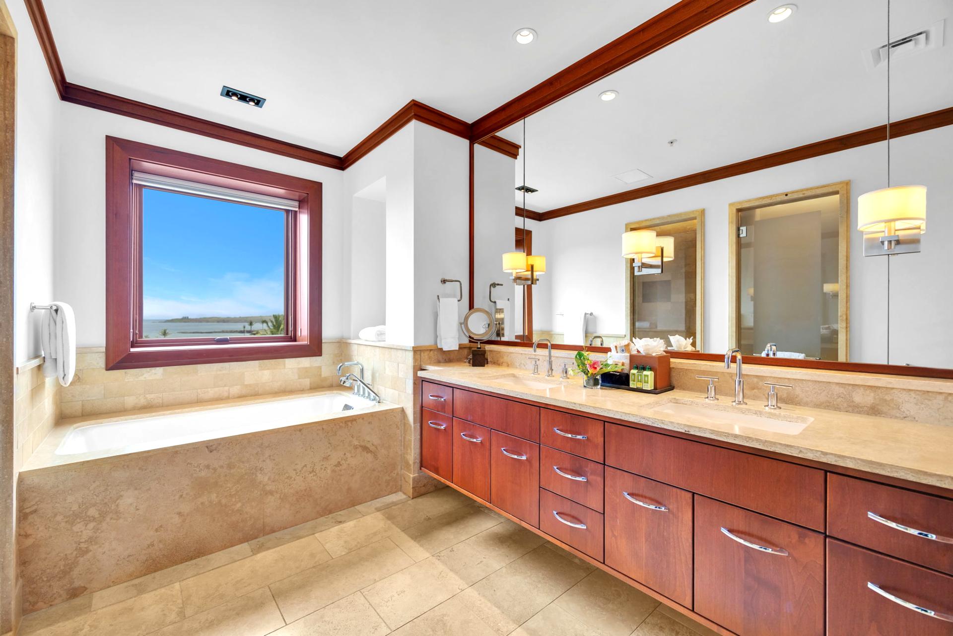 Guest bathroom with double vanities and soaking tub beneath a view-filled window