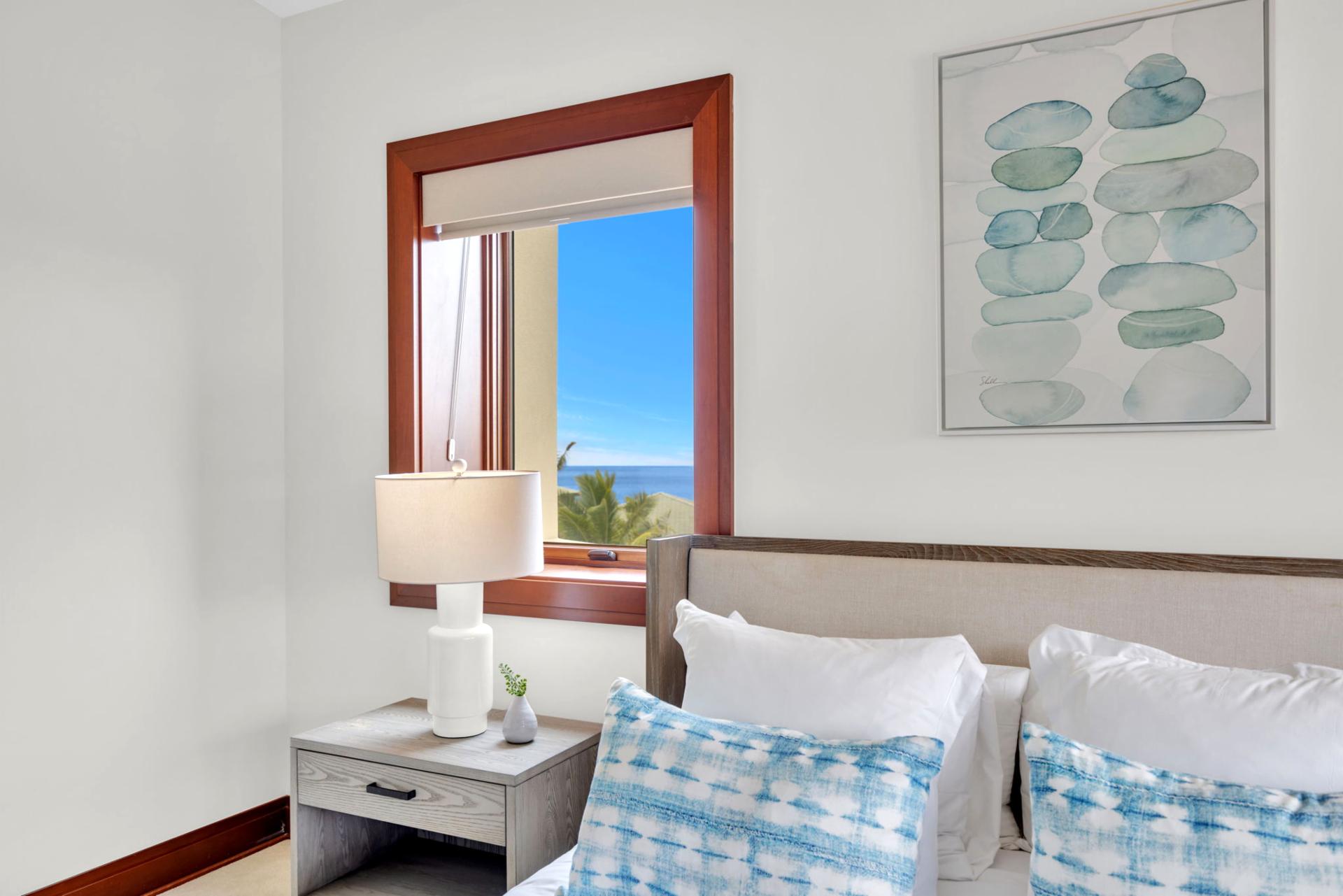 Serene bedroom with soft blues and sunlight pouring in from ocean-facing windows

