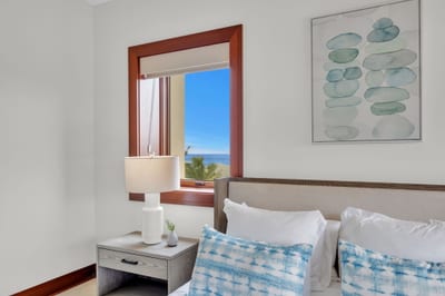 Serene bedroom with soft blues and sunlight pouring in from ocean-facing windows