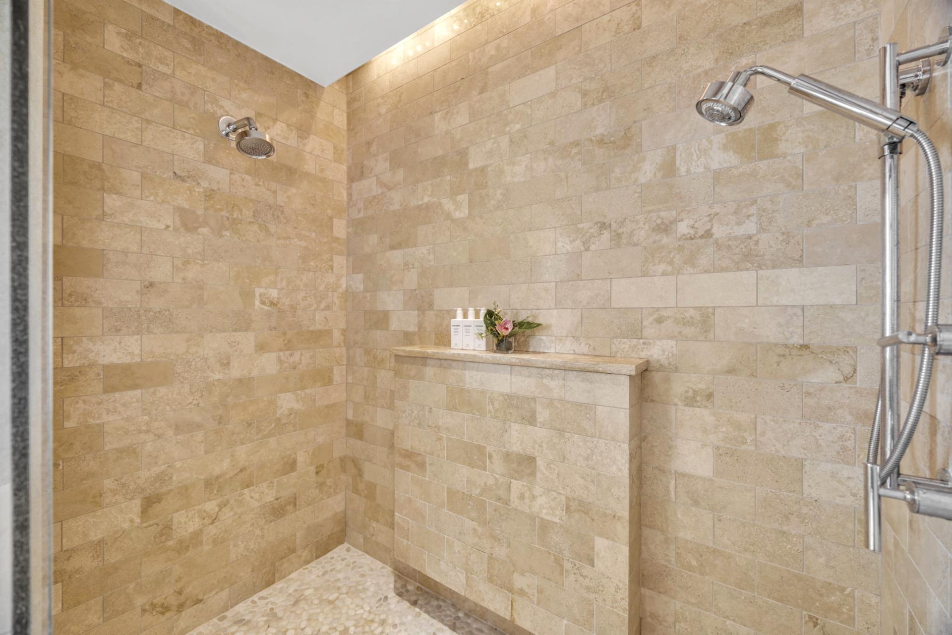 Spacious walk-in shower with warm stone tile for a rejuvenating rinse