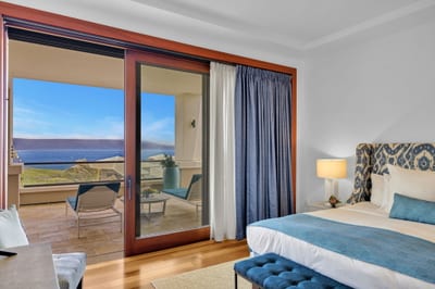 Master bedroom with plush bedding and balcony access to ocean serenity