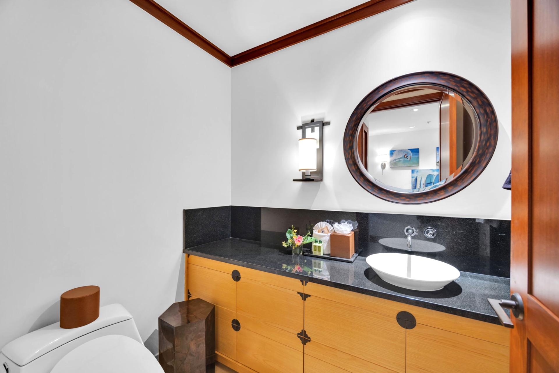 Unique half-bath with round mirror and bold black granite accents