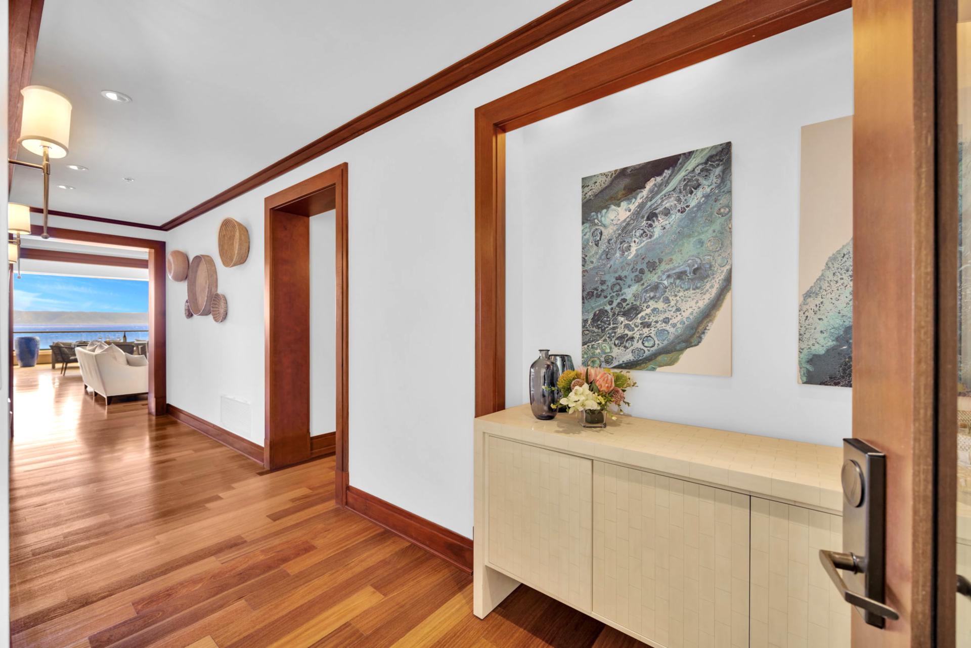 Elegant entryway with warm wood floors and artful island decor

