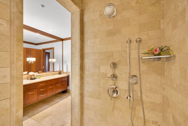 The walk in shower features a sleek tile design