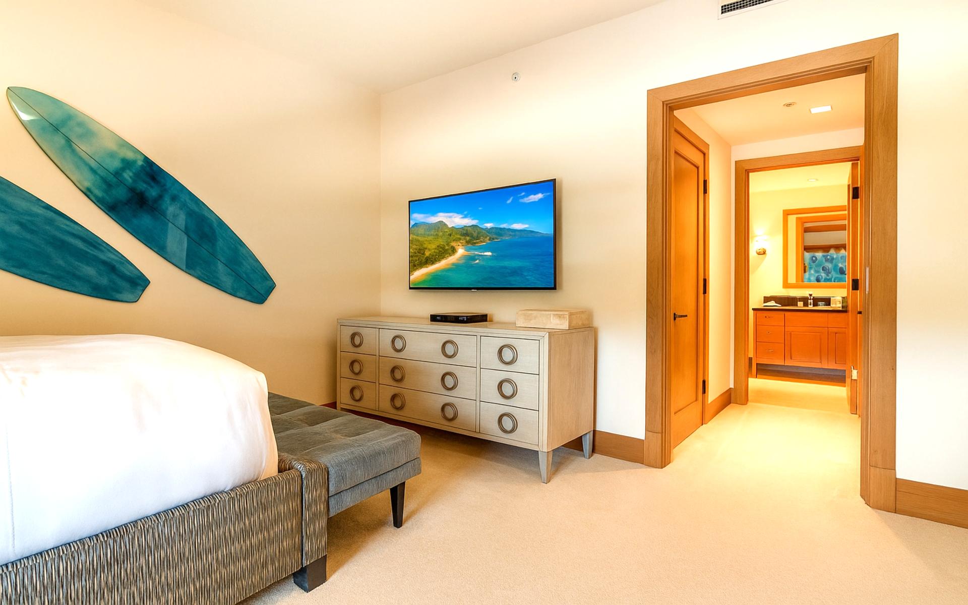 Natural light pours in through the window, framing restful beds dressed in inviting coastal tones