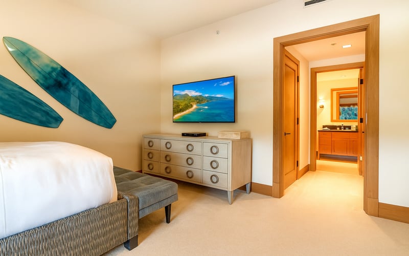 Natural light pours in through the window, framing restful beds dressed in inviting coastal tones