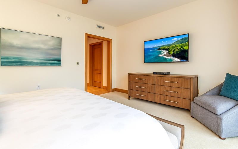 Gentle light filters through sheer drapes, casting soft shadows across the serene king-sized sleeping retreat