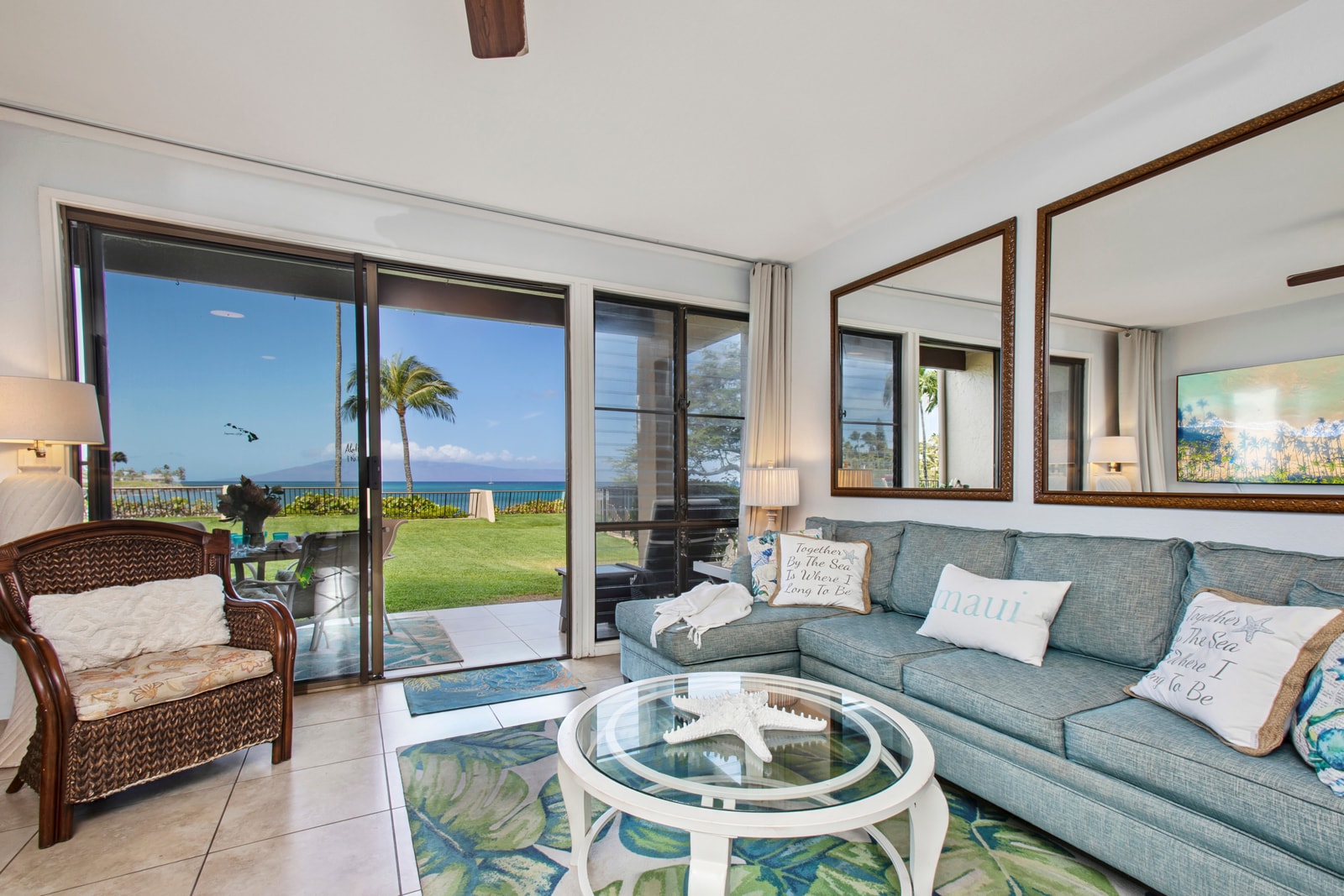 Bright living room with large, sliding glass doors that open directly onto the oceanfront lanai NAP-B13