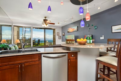 Modern coastal kitchen with ocean views, colorful pendant lighting, and island bar for relaxing tropical gatherings