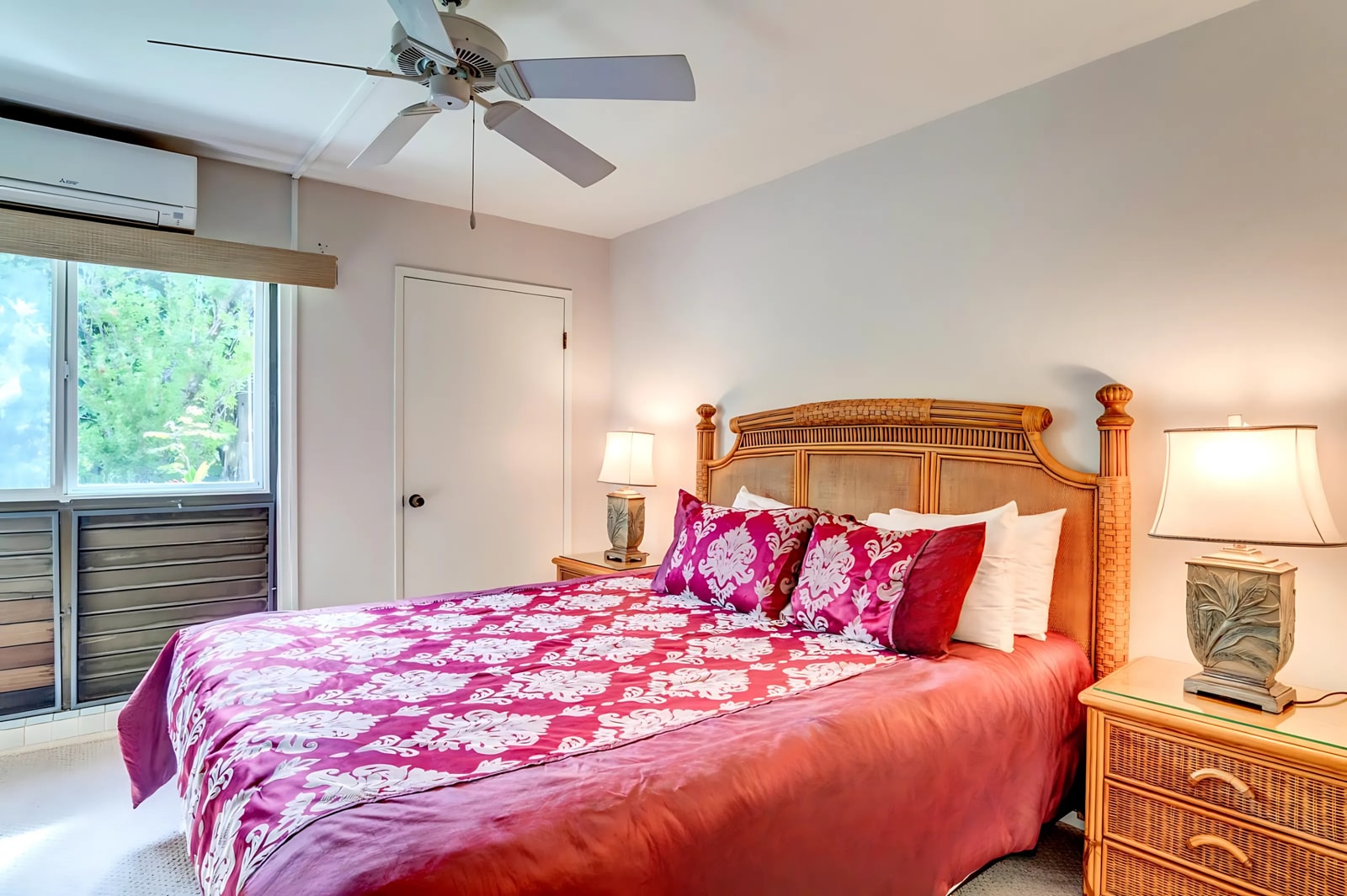 The master bedroom features a bold tropical bedspread, natural light streaming through the lanai doors, and a peaceful vacation ambiance. NAP-B43