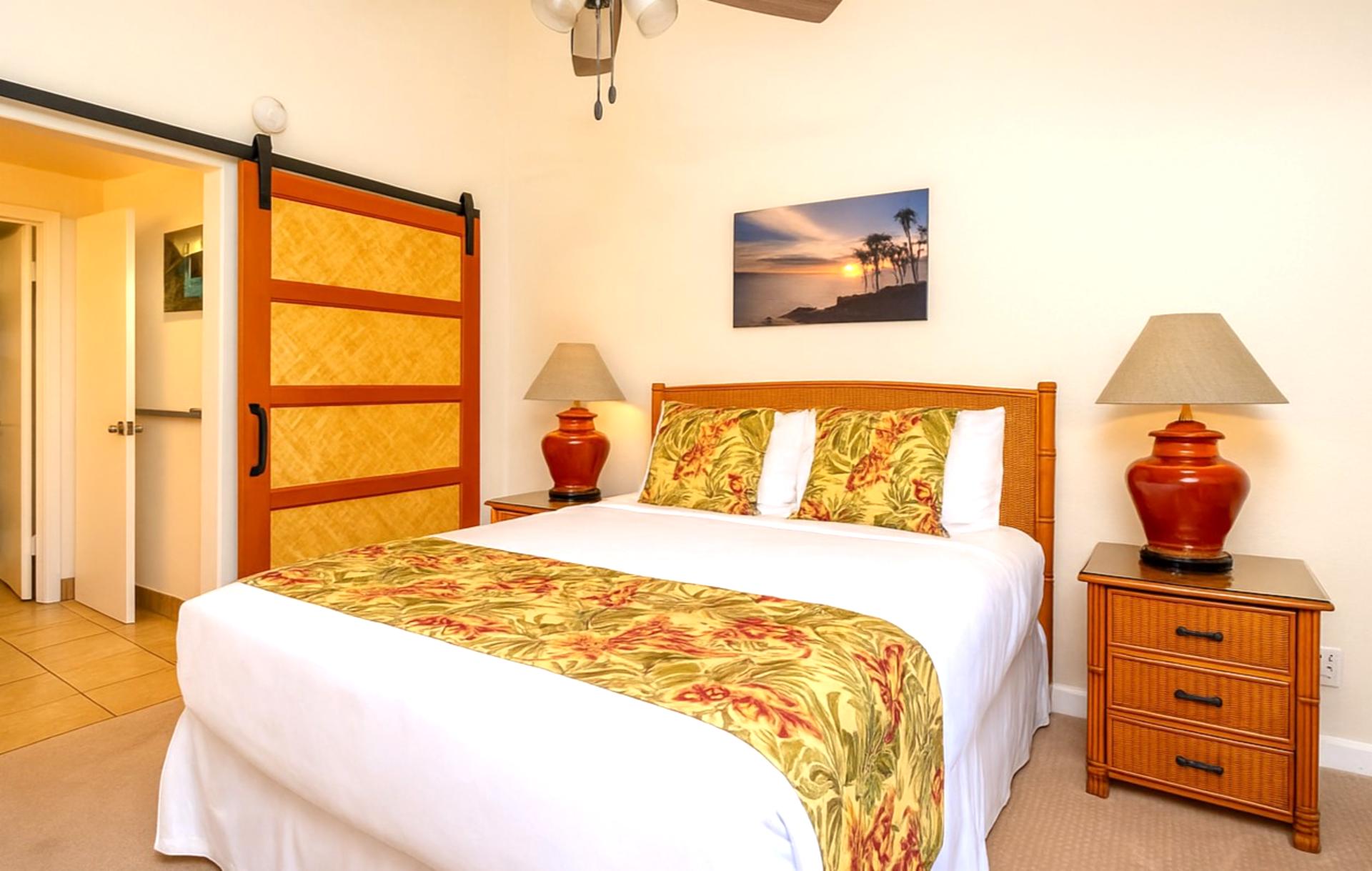 Elegant master with island-inspired bedding, tropical wood furnishings, garden views, and a stylish barn door