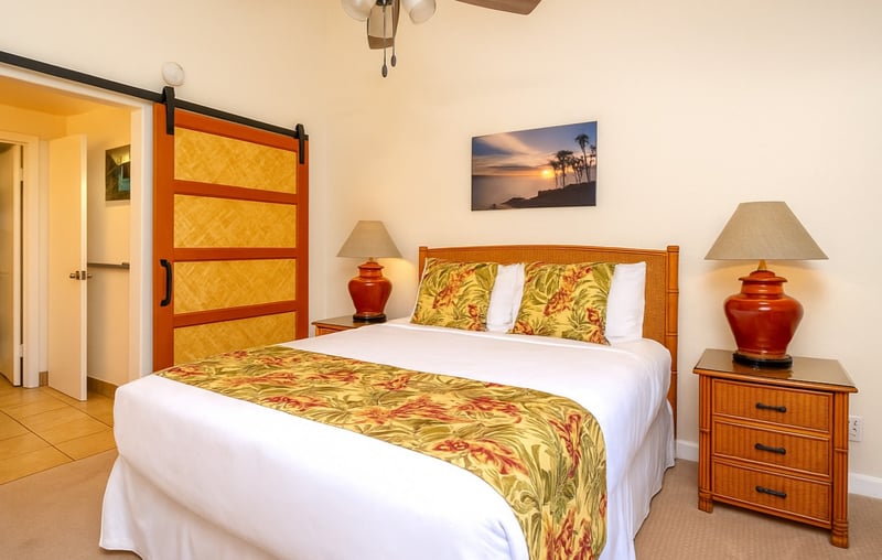 Elegant master with island-inspired bedding, tropical wood furnishings, garden views, and a stylish barn door NAP-C18