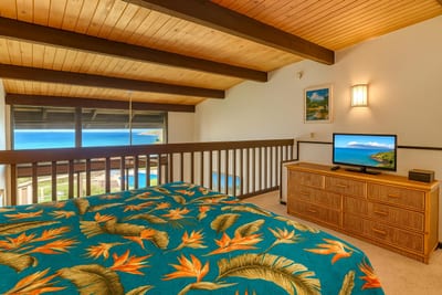 Lofted master suite with rich wood ceilings, tropical bedding, natural light, and serene views from wide windows NAP-C42