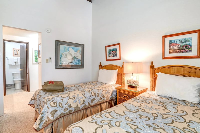 Comfort meets island charm with twin beds, natural wood tones, curated art, and a cozy, light-filled setting