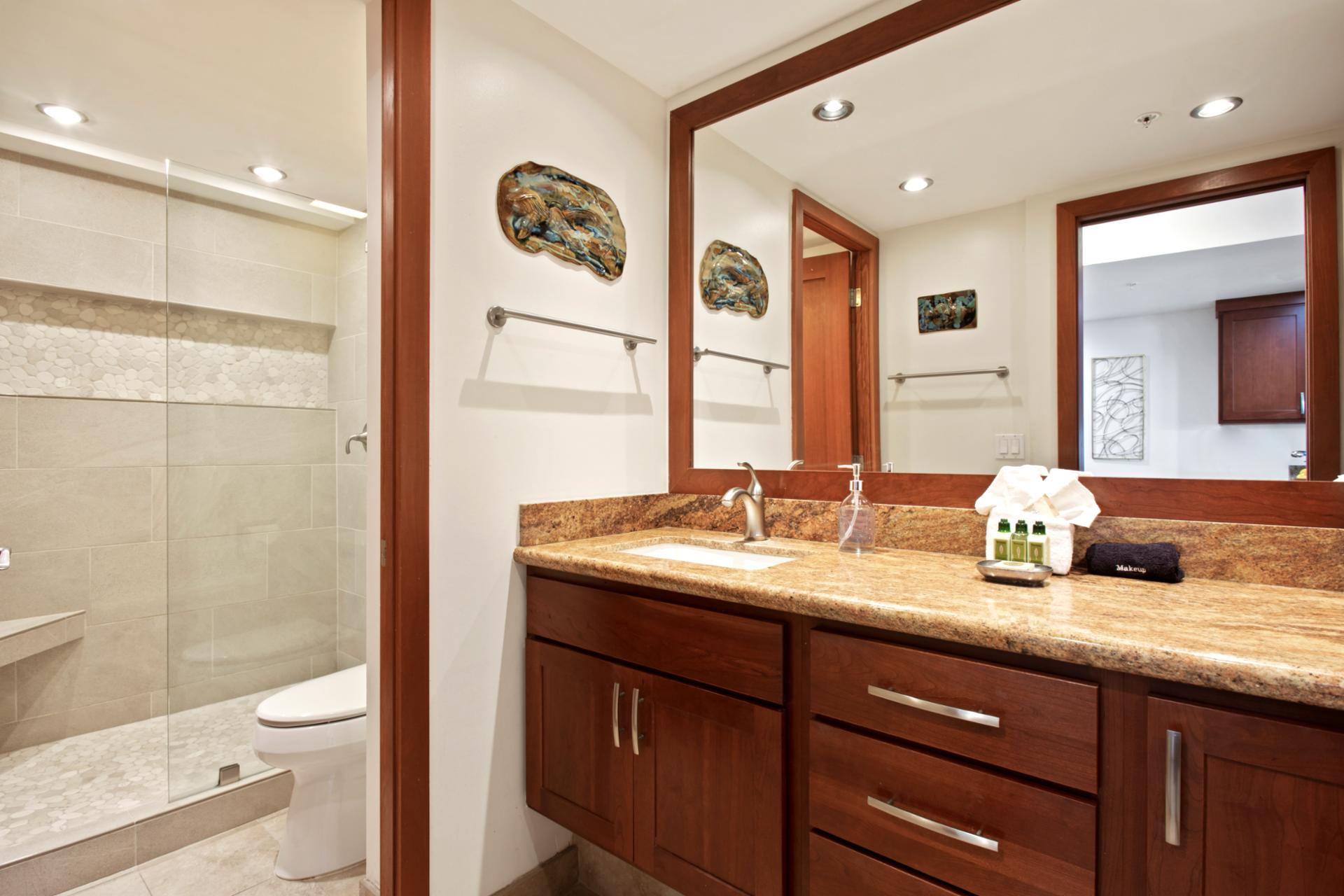 The walk-in shower is wrapped in smooth sandstone tile, accented by a horizontal mosaic band and an angled bench for comfort WH2-661