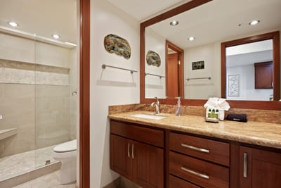 The walk-in shower is wrapped in smooth sandstone tile, accented by a horizontal mosaic band and an angled bench for comfort
