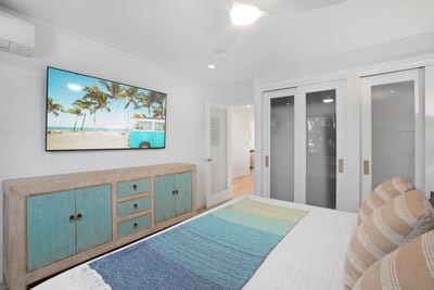 This master bedroom is a palette of seafoam and sand, anchored by a king bed as wide as a beachside hammock dream