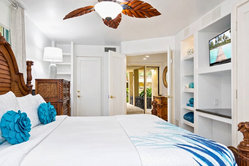 Retreat to the master bedroom featuring a luxurious king-size bed, ceiling fan, and cozy island decor. Wake up to serene views just beyond your windows.