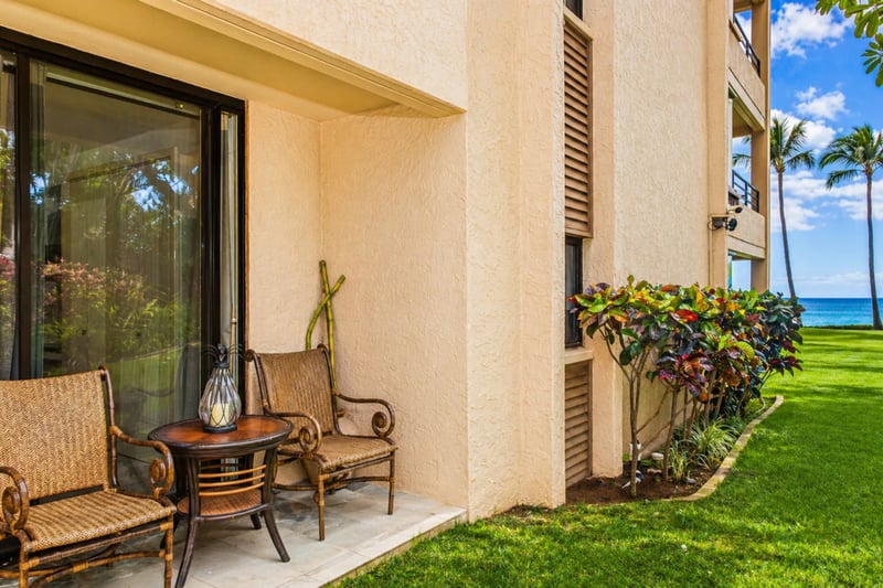 Private ground-floor lanai at Polo Beach Club 109, with rattan seating just steps from the lawn and ocean beyond.