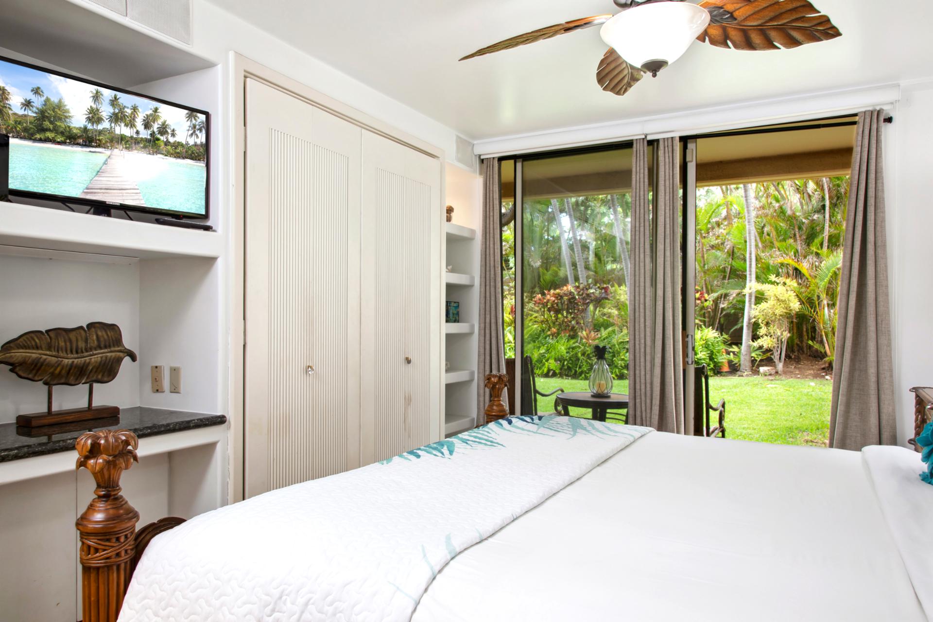 Retreat to the master bedroom featuring a luxurious king-size bed, ceiling fan, and cozy island decor. Wake up to serene views just beyond your windows.