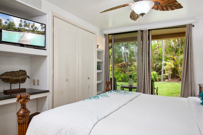Retreat to the master bedroom featuring a luxurious king-size bed, ceiling fan, and cozy island decor. Wake up to serene views just beyond your windows.