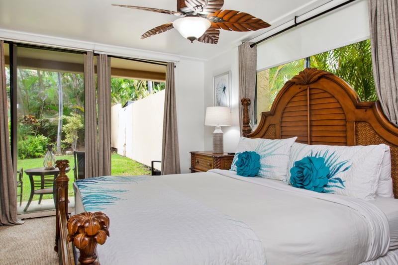 Retreat to the master bedroom featuring a luxurious king-size bed, ceiling fan, and cozy island decor. Wake up to serene views just beyond your windows.