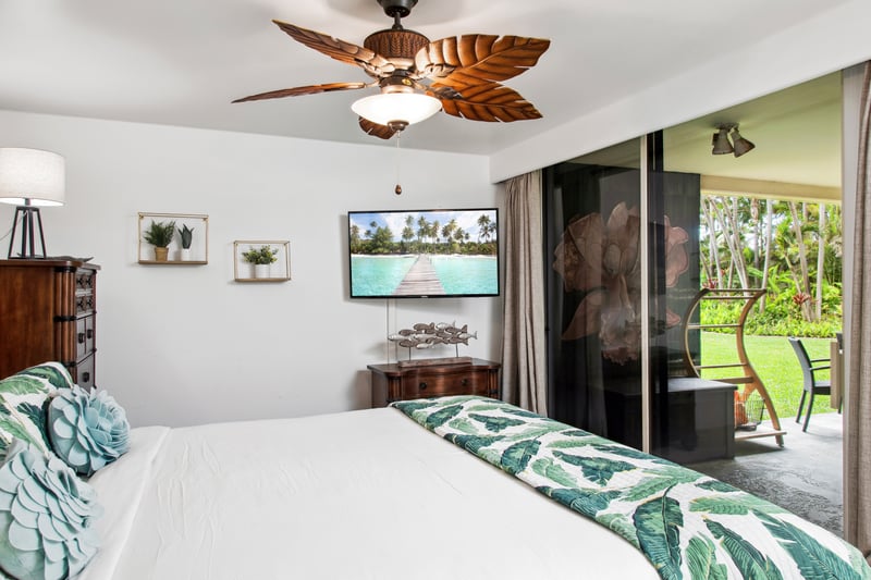 Wake up to lush garden views through expansive glass doors in this serene, tropically inspired master retreat