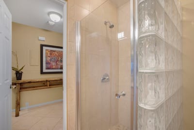 With glass block walls and gleaming tile, the shower feels like a spa day held inside a shimmering sandcastle