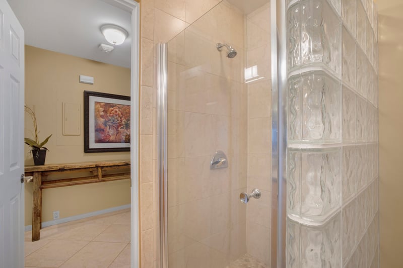 With glass block walls and gleaming tile, the shower feels like a spa day held inside a shimmering sandcastle