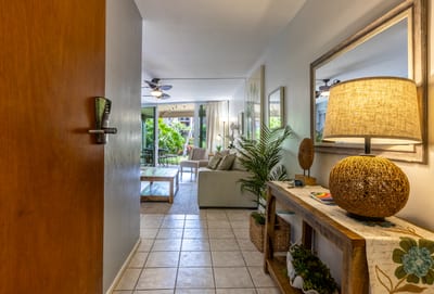 A welcoming hallway leads to an airy open-concept living space with tropical accents.