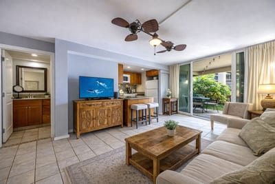 Smart layout with open kitchen and living area leading to an outdoor dining space under the palms.