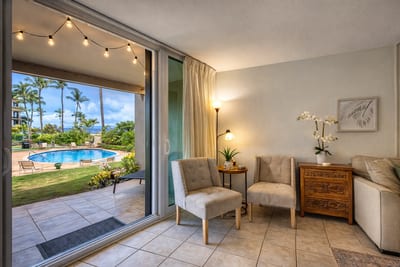 Bright and inviting living area with direct access to a lush garden patio and poolside view.