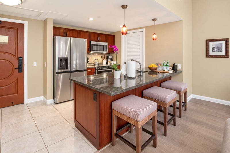 Cook with ease in the fully equipped gourmet kitchen featuring a large prep island, modern appliances, and casual bar seating. HKH-114