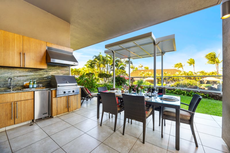 Outdoor living at Honua Kai HKH-150 — pergola-covered patio connecting the BBQ kitchen to garden and grounds beyond
