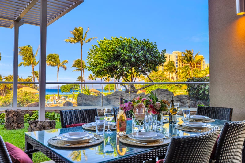 Lanai garden at Honua Kai HKH-150 — red ginger blooms and lounge seating beneath the private pergola