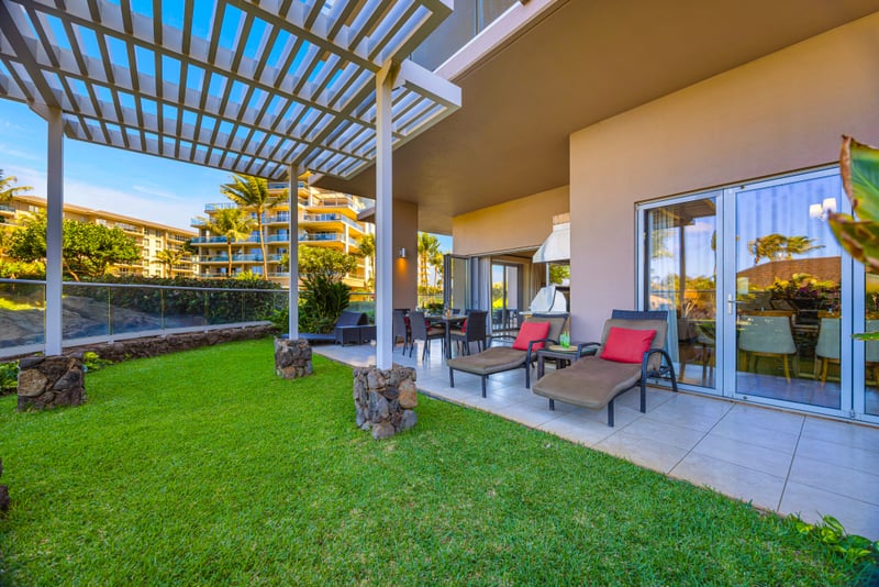 Outdoor living space at Honua Kai HKH-150 — dining table, BBQ kitchen, and lounge seating beneath the pergola