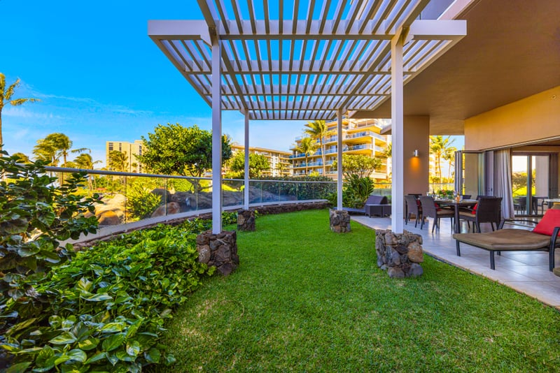 Pergola lanai at Honua Kai HKH-150 — outdoor kitchen and dining set against palm-lined resort grounds