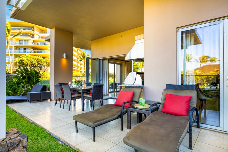 Private lanai at Honua Kai HKH-150 — pergola-covered outdoor kitchen and dining framed by palm trees