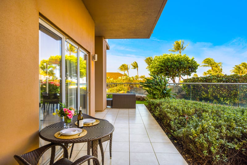 Lanai bistro table at Honua Kai HKH-150 — wine and floral centerpiece framed by garden and pergola views
