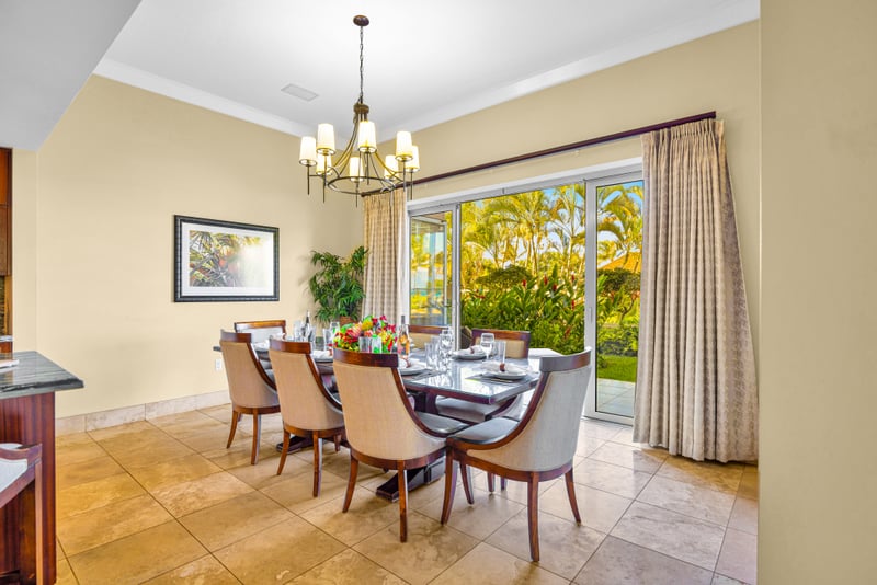 Dining room at Honua Kai HKH-150 — table for eight beneath a chandelier, framed art, and garden-view sliders