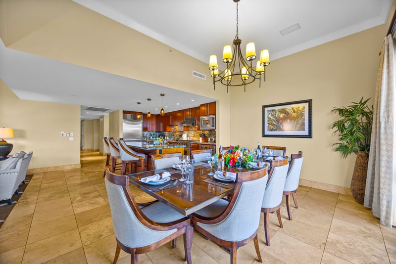 Dining room at Honua Kai HKH-150 — chandelier-lit table for eight opening directly to the kitchen