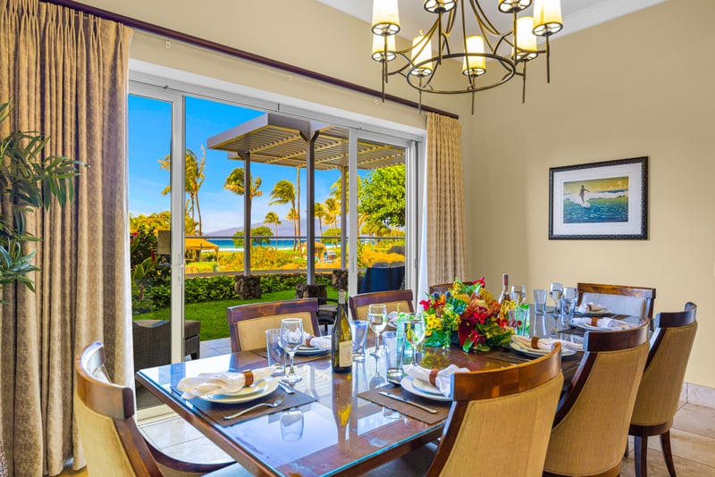 Formal dining room at Honua Kai Hokulani 150 — seating for eight beneath a wrought-iron chandelier with a direct ocean view through the lanai doors