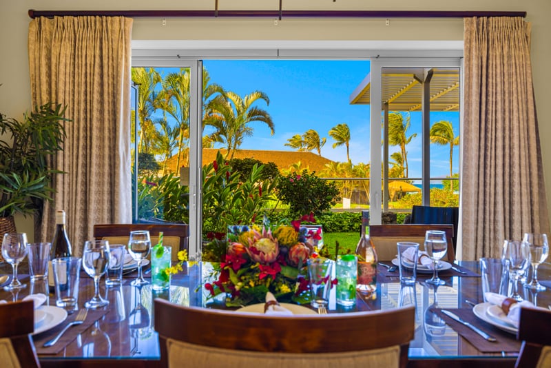 Dining room at Honua Kai HKH-150 — table for eight with a floral centerpiece beside garden-view sliding doors