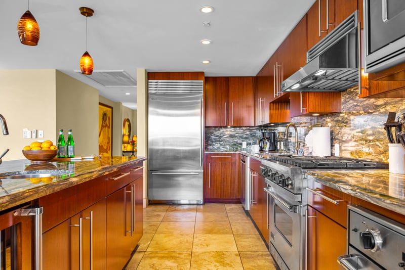 Kitchen at Honua Kai HKH-150 — Sub-Zero refrigerator, gas range, and stone backsplash with Hawaiian artwork