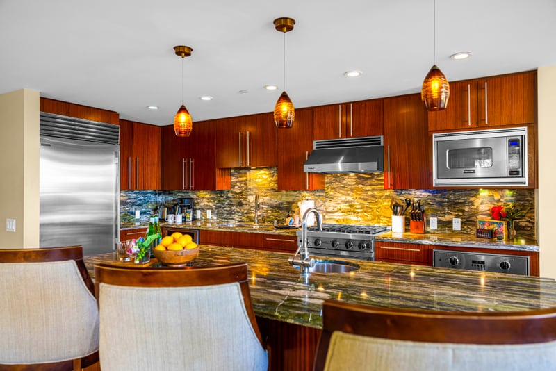 Kitchen island seating at Honua Kai HKH-150 — granite bar for three opening to the dining room and living room beyond