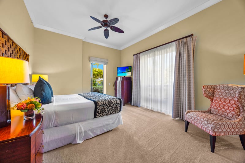 Guest bedroom at Honua Kai HKH-150 — woven headboard king bed, smart TV, and direct garden access