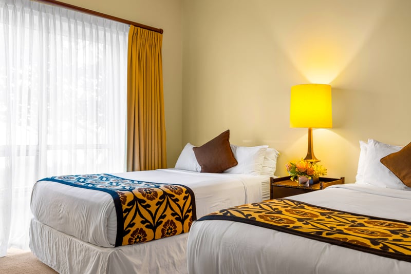 Guest bedroom at Honua Kai HKH-150 — two queen beds with warm brown accent pillows