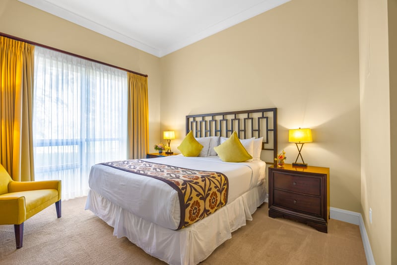 Guest bedroom at Honua Kai HKH-150 — king bed with citrus accent pillows and a private lanai