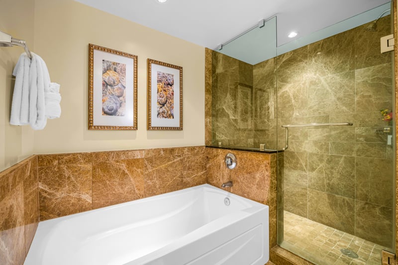 Guest bathroom at Honua Kai HKH-150 — freestanding soaking tub and glass walk-in shower with coastal artwork